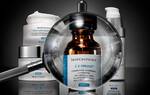 Vergroßerte Ansicht einer Flasche SkinCeuticals C E Ferulic mit verschiedenen Hautpflegeprodukten im Hintergrund.