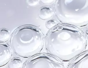 Gros plan sur des bulles d&aposeau transparentes flottant a la surface, creant un effet de lumiere et de reflexions.