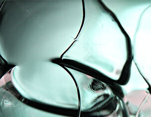 Gros plan sur des formes de verre translucide et ondulees, creant un effet de lumiere et de texture organique.