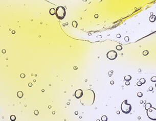 Des gouttes d&aposeau et des bulles d&aposair se formant dans un liquide jaunatre, creant un effet translucide et lumineux.