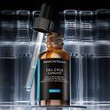 Flacon de serum Cell Cycle Complex de SkinCeuticals avec le compte-gouttes deploye, devant des flacons flous en arriere-plan
