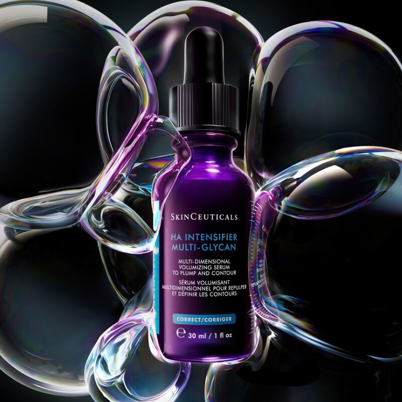 Un flacon de serum SkinCeuticals H.A. Intensifier entoure de bulles iridescentes.