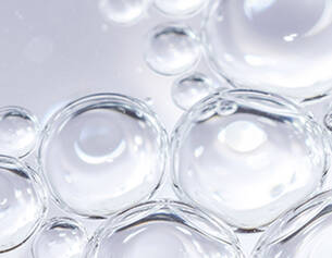 Gros plan sur des bulles d&aposeau transparentes flottant a la surface, creant une texture delicate et lumineuse.