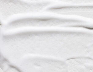 Texture lisse d&aposune creme blanche etalee sur une surface, mettant en evidence des ondulations delicates.
