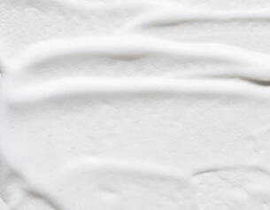 Texture lisse d&aposune creme blanche etalee sur une surface, mettant en evidence des ondulations delicates.