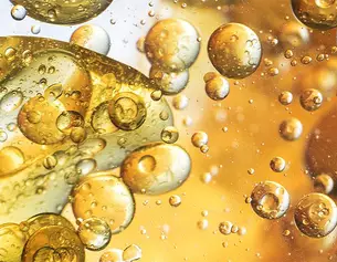 Des bulles d&aposhuile doree flottent dans un liquide translucide, creant un effet visuel dynamique et intriguant.