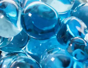A close-up of shiny blue glass marbles, reflecting light and showcasing varying shades of blue.