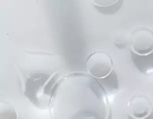Gouttes d'eau et bulles sur une surface blanche, creant un effet de transparence et de legerete.