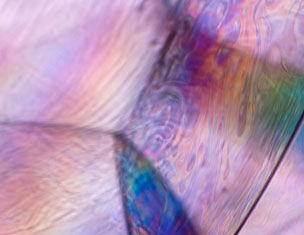 Abstract close-up of colorful, iridescent patterns resembling light refracted through a soap bubble.