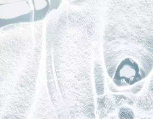 Abstract image showing a close-up view of a textured, icy surface with subtle variations in light and shadow.