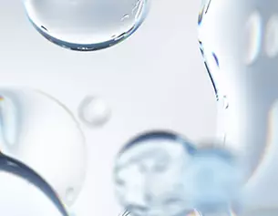 Close-up of translucent water droplets with soft reflections on a light background, creating an ethereal, fluid effect.