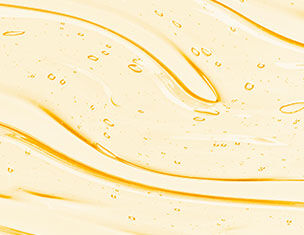 Close-up of a smooth, flowing texture of golden oil with small bubbles, creating a glossy and dynamic pattern.