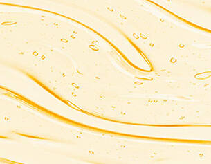 Close-up of a smooth, flowing texture of golden oil with small bubbles, creating a glossy and dynamic pattern.