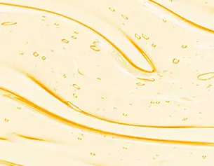 Gros plan d’une texture d’huile doree lisse et fluide parsemee de petites bulles, creant un motif brillant et dynamique.