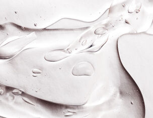 Gouttes d'eau sur une surface lisse et brillante, creant des reflets et des textures translucides.