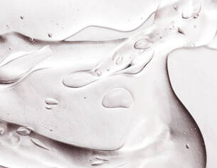 Gouttes d'eau sur une surface lisse et brillante, creant des reflets et des textures translucides.