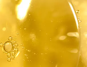 Gros plan sur des bulles d'air dans un liquide visqueux et dore, creant un effet lumineux et texture.