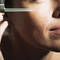 Une femme applique un serum sur son visage avec un compte-gouttes.