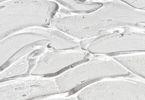 Abstract close-up of smooth, translucent gel texture with flowing, wavy patterns on a light surface.