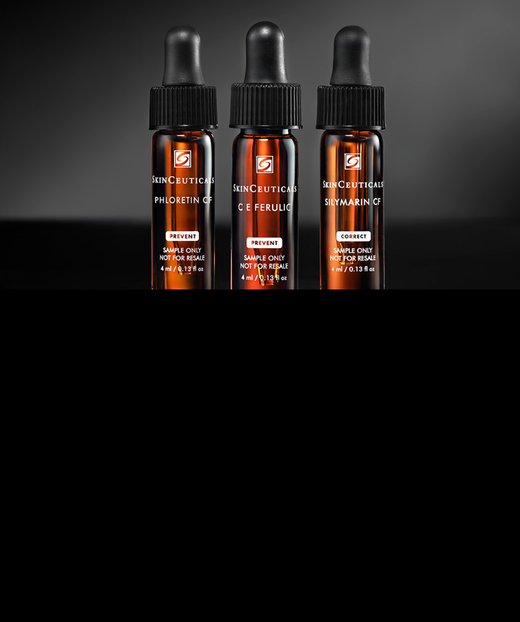 Trois flacons de serum en verre marron avec compte-gouttes, sur un fond noir.