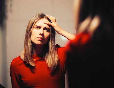 Femme se regardant dans le miroir et pointant du doigt les deux rides du lion