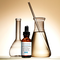 Un flacon de serum SkinCeuticals "Silymarin CF" avec des flacons et un tube en verre, le tout sur un fond lumineux.