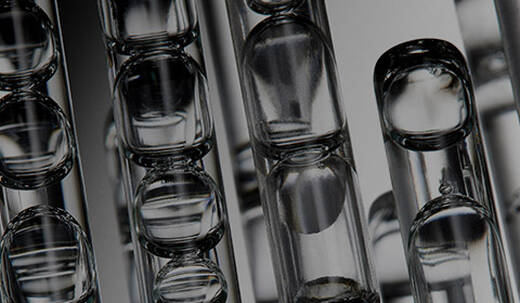 Gros plan d'un compte-gouttes transparent distribuant quelques gouttes de serum sur une surface blanche