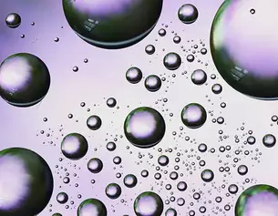 Gros plan de bulles irisees de tailles variees flottant sur un fond violet doux.