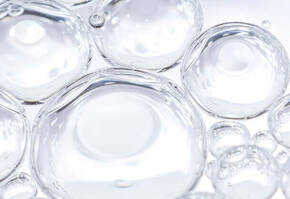 Boule de bulles d'eau translucides flottant dans un fond clair, creant une texture legere et aerienne.