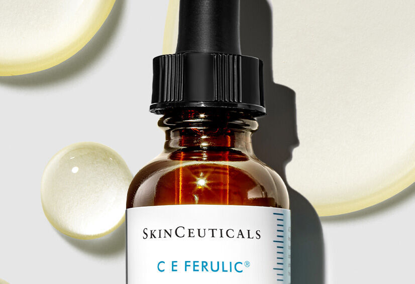 Flacon de serum SkinCeuticals C E Ferulic, entoure de gouttes transparentes sur fond clair.
