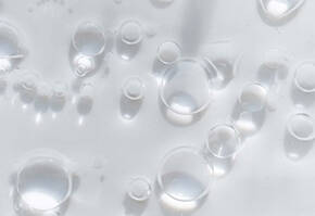 Gouttes d'eau claires et bulles d'air flottant a la surface d'un liquide, creant un effet translucide.