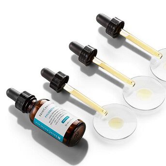 Flacons de serum avec compte-gouttes, disposes sur une surface blanche, mettant en avant un flacon en verre brun et des pipettes transparentes.