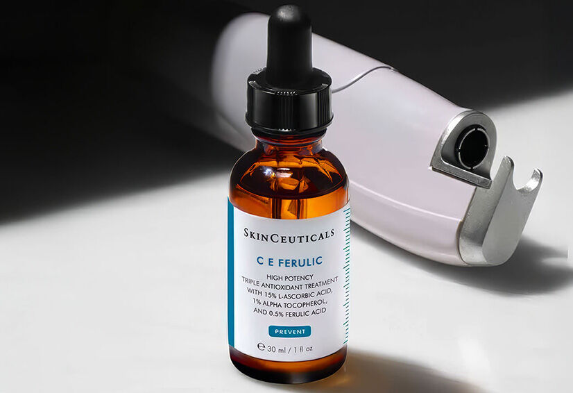 Flacon de serum SkinCeuticals C E Ferulic avec gouttelette, sur fond clair, entoure de gouttes d'huile.