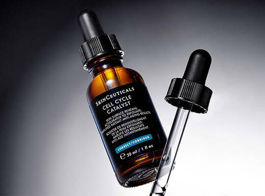 Flacon de serum en verre sombre avec pipette, sur fond noir.