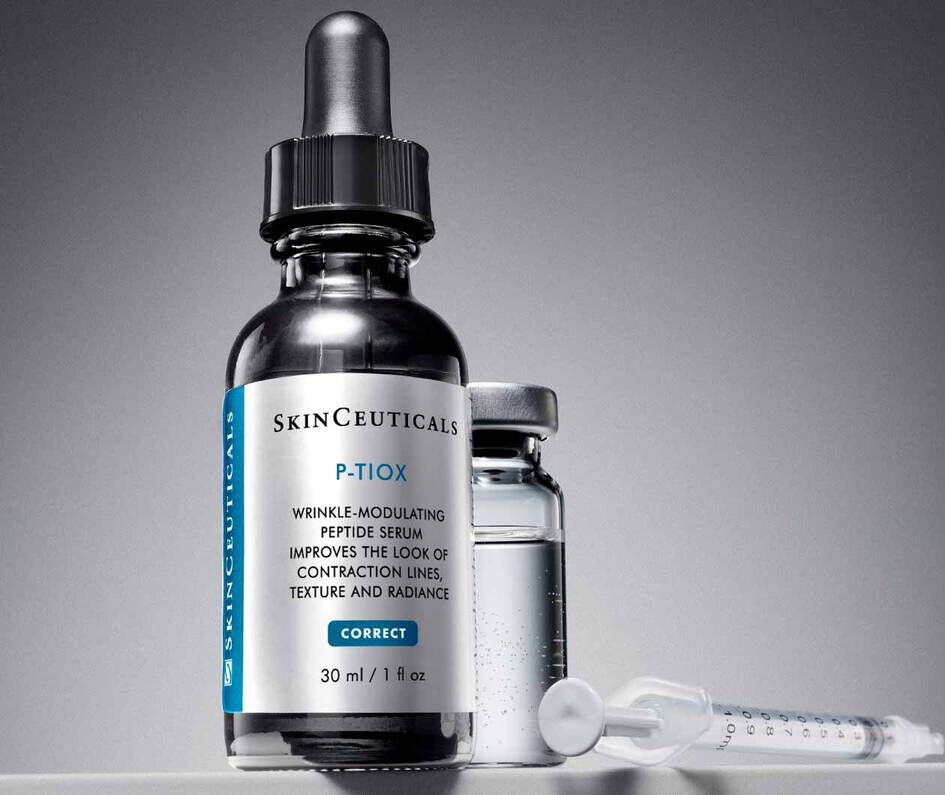 Flacon de serum anti-rides SkinCeuticals P-TIOX, a cote d'une petite ampoule et d'une seringue, sur fond gris.