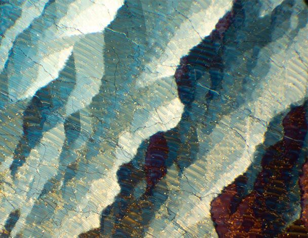 Des motifs abstraits aux couleurs bleues, blanches et dorees, evoquant une texture en vagues sur fond sombre.