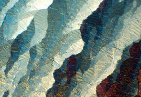 Des motifs abstraits aux couleurs bleues, blanches et dorees, evoquant une texture en vagues sur fond sombre.