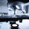 Un microscope moderne avec des objectifs en gros plan, mettant en evidence la platine et l'eclairage en dessous.
