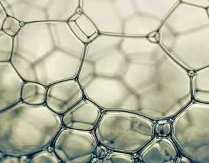 Des bulles de savon translucides formant un motif hexagonal complexe, capturant la lumiere avec douceur.