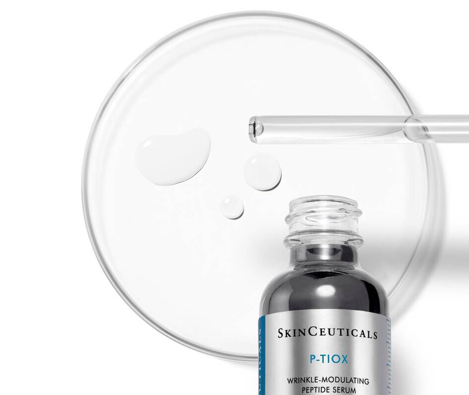 Flacon de serum SkinCeuticals P-TIOX avec des gouttes sur une plaque de Petri, mettant en avant sa texture.