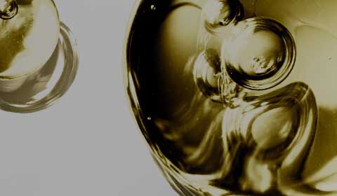 Trois flacons de serum en verre fonce sur un fond noir, avec un logo indiquant 20 ans d'existence.