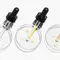 Trois pipettes avec des serums de differentes couleurs reposent sur des dishes de Petri transparentes.