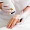 Une main de patient recoit un traitement esthetique avec un appareil en cours d'utilisation par un professionnel en gants.